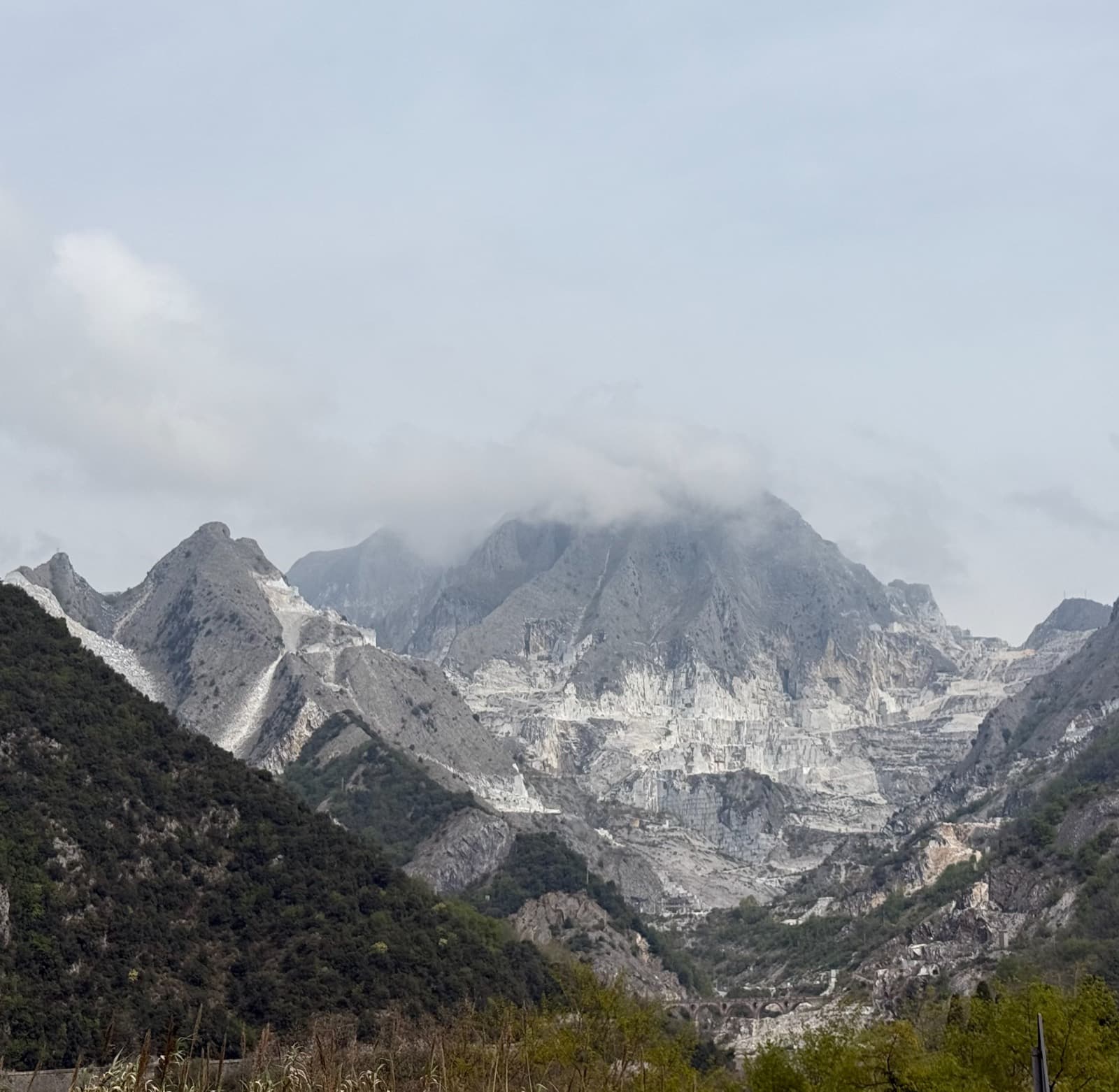 The marble basin above Carrara under low cloud, white terraces cut into grey rock