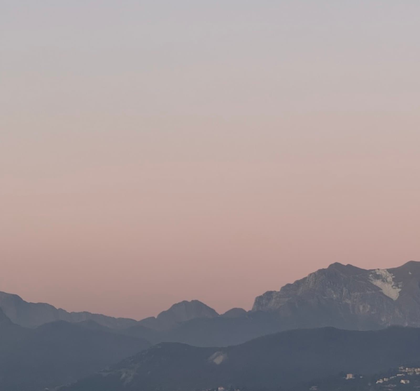 The Apuan Alps turning pink above a dark ridge at dusk, the last light on the marble
