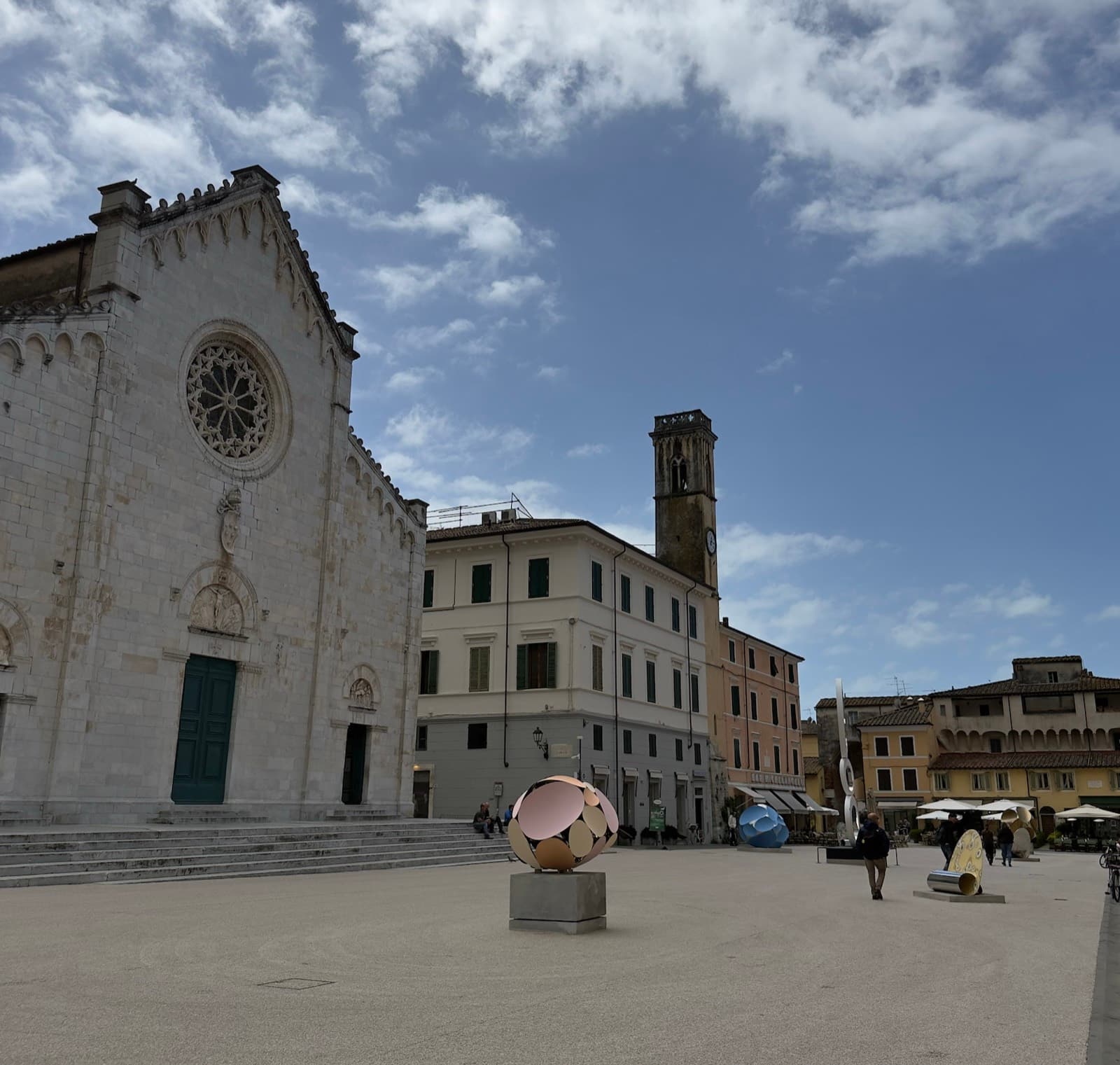 The marble facade of the duomo on the square at Pietrasanta, with sculpture standing in the open